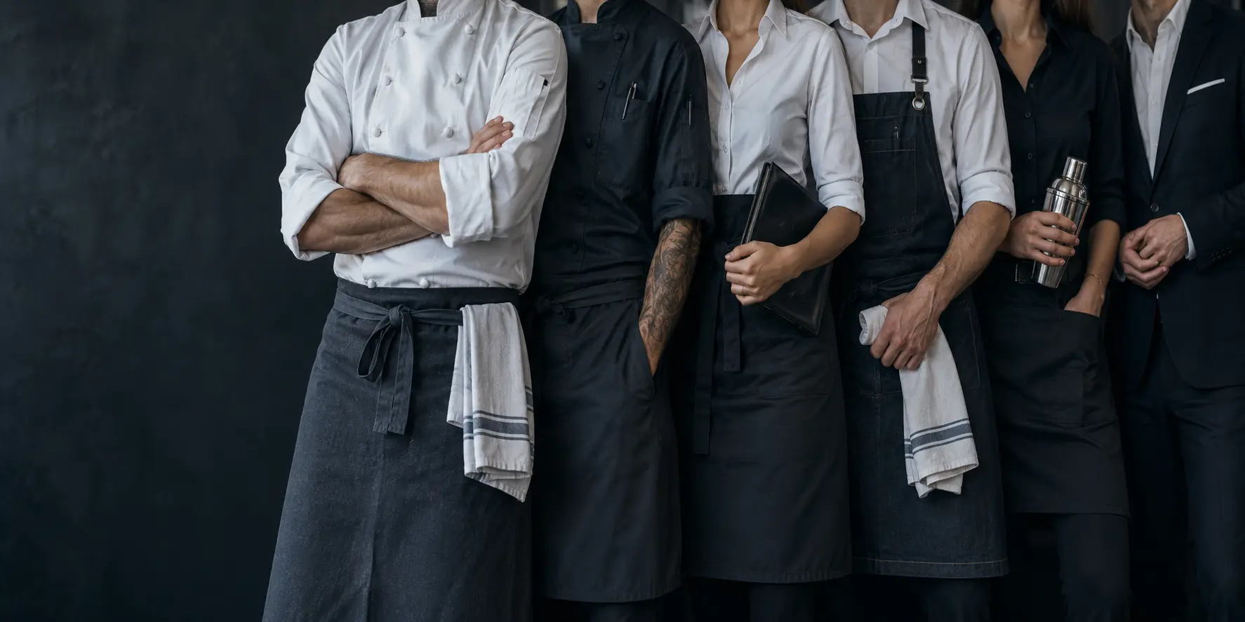 Restaurant team in chef jackets, aprons, and service attire