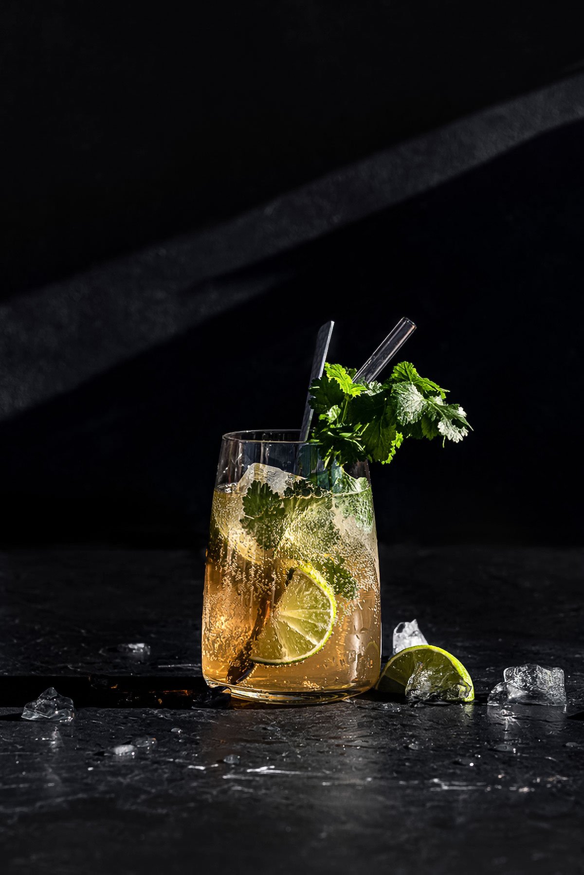 A tall cocktail with lime, fresh herbs and ice