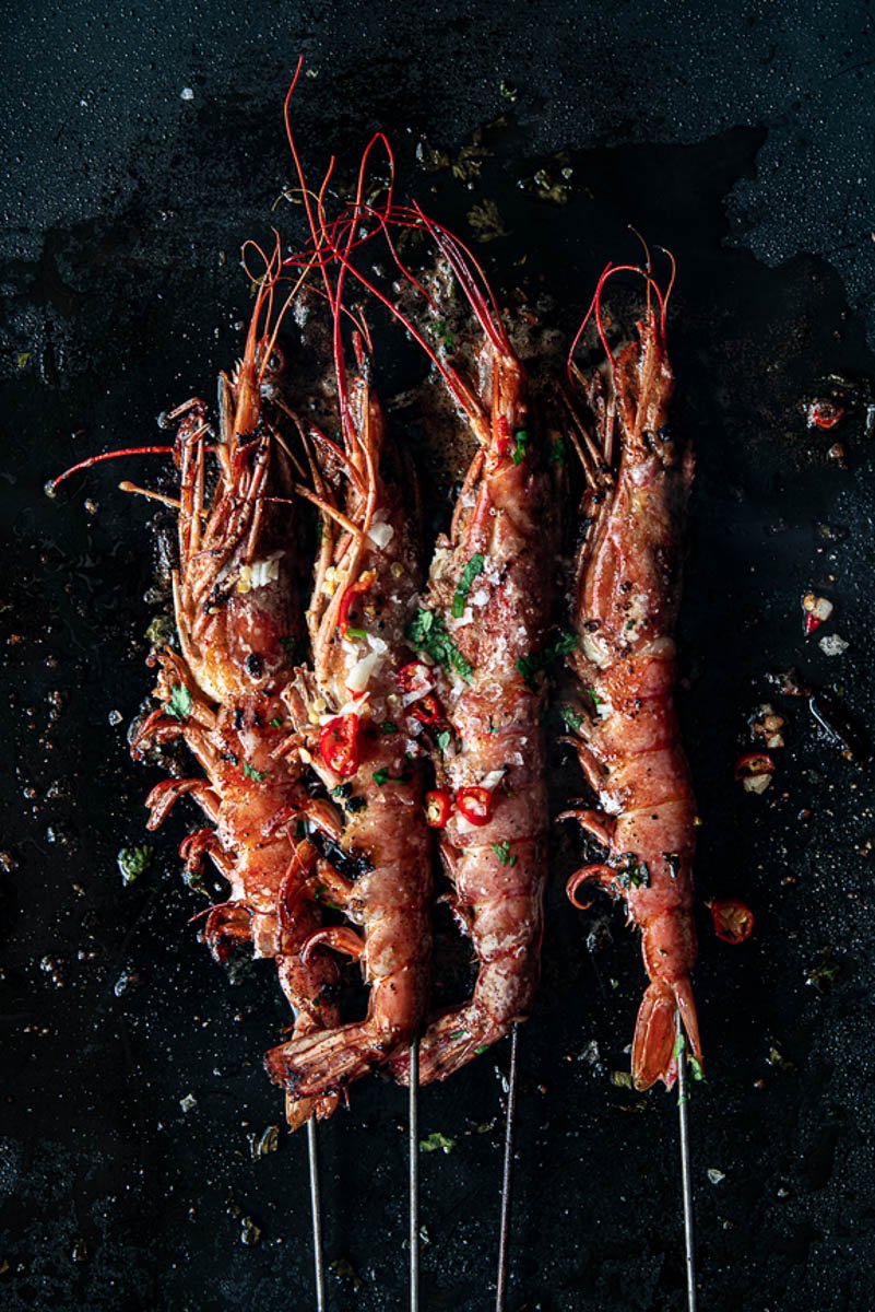 Grilled prawns with herbs and chili on dark stone